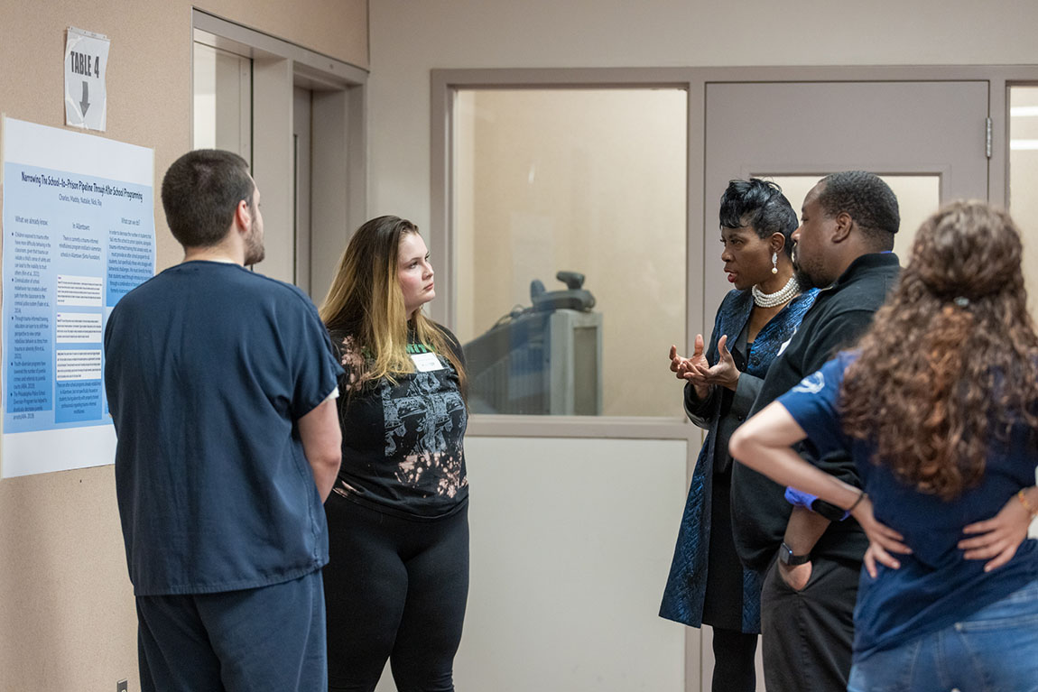 Two Inside-Out students speak with a woman and man who came to hear their presentation